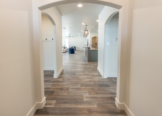 hall featuring recessed lighting, baseboards, dark wood-type flooring, and arched walkways