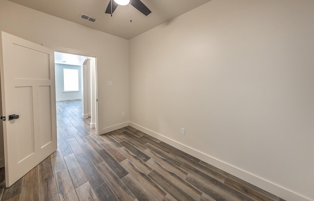 empty room with visible vents, baseboards, dark wood-style flooring, and a ceiling fan