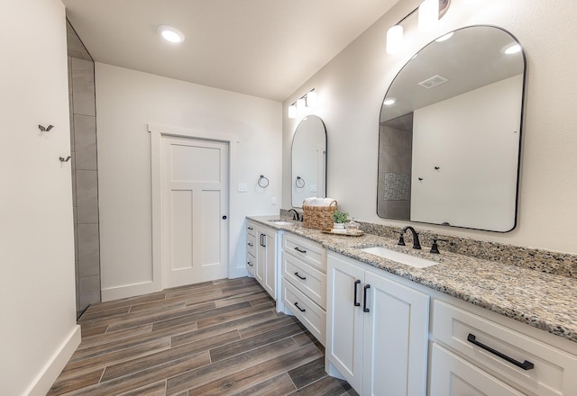 bathroom with double vanity, visible vents, wood finish floors, and a sink