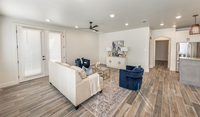 living room featuring light wood-type flooring, visible vents, recessed lighting, arched walkways, and ceiling fan