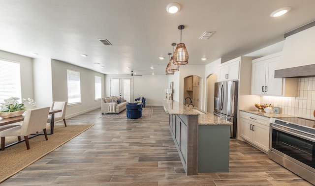 kitchen with tasteful backsplash, visible vents, open floor plan, stainless steel appliances, and a sink