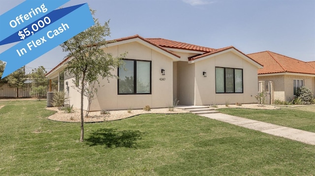 view of front of house featuring a front yard, a tiled roof, fence, and stucco siding