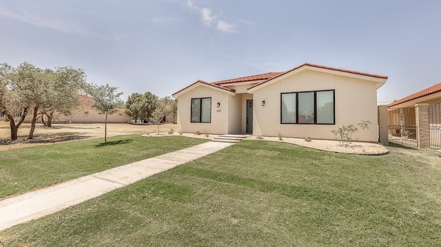 view of front of home featuring stucco siding, a tile roof, a front lawn, and fence