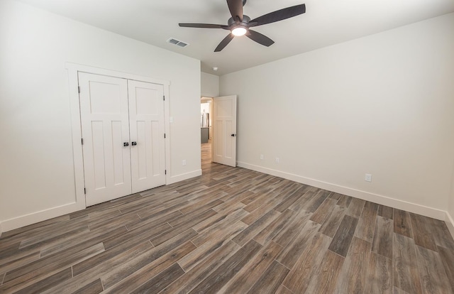 unfurnished bedroom with wood finished floors, visible vents, baseboards, ceiling fan, and a closet