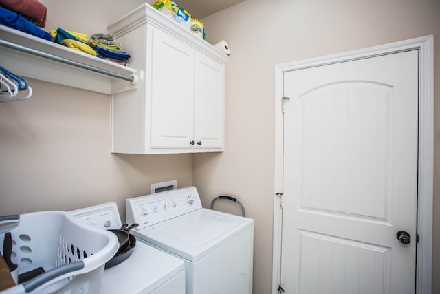 clothes washing area featuring cabinets and washer and dryer