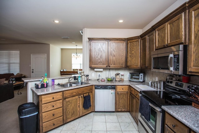 kitchen featuring sink, an inviting chandelier, backsplash, stainless steel appliances, and kitchen peninsula