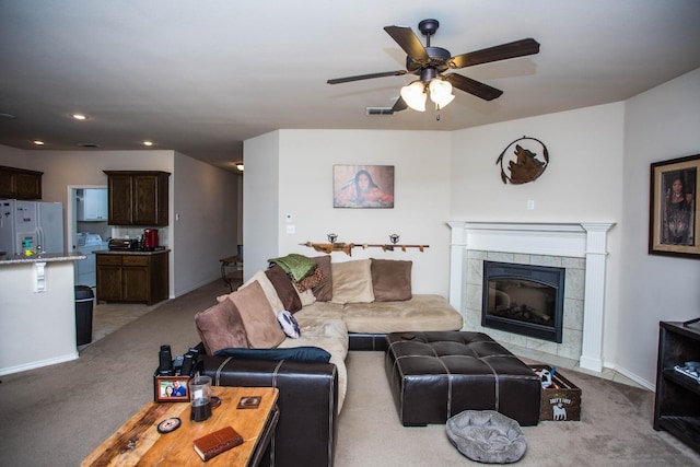 carpeted living room with a tile fireplace and ceiling fan