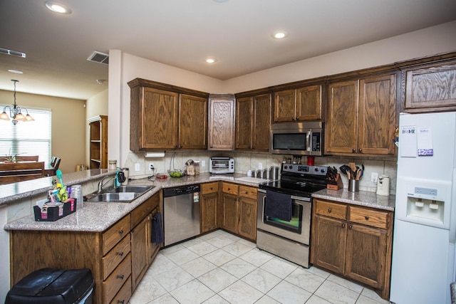 kitchen with appliances with stainless steel finishes, pendant lighting, tasteful backsplash, sink, and light stone countertops