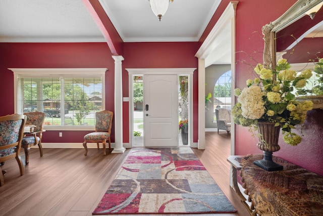 foyer entrance with crown molding, wood-type flooring, and ornate columns