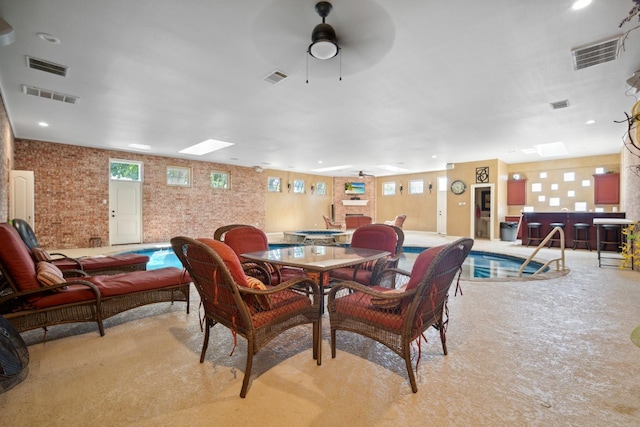 dining area featuring brick wall, a healthy amount of sunlight, and ceiling fan