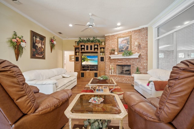 living room with a fireplace, hardwood / wood-style flooring, ornamental molding, ceiling fan, and a textured ceiling