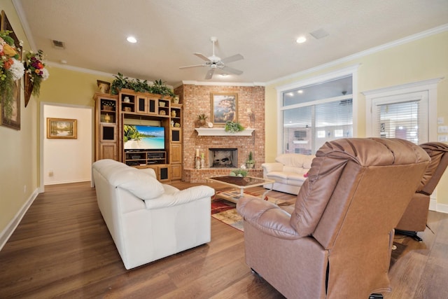 living room featuring hardwood / wood-style flooring, ornamental molding, a fireplace, and a textured ceiling