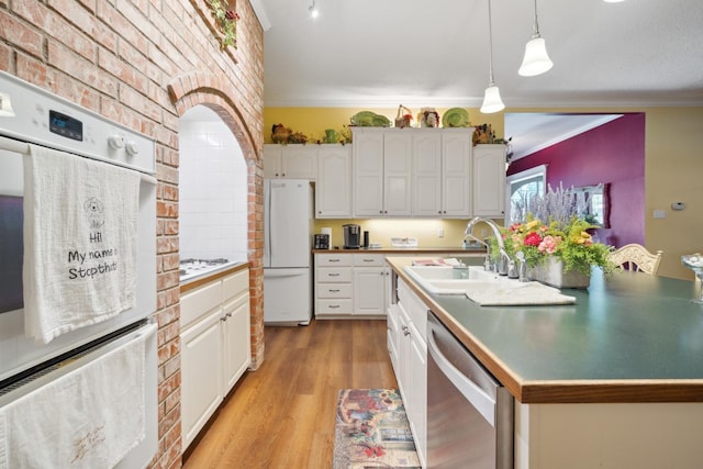 kitchen with sink, white appliances, white cabinetry, an island with sink, and decorative light fixtures