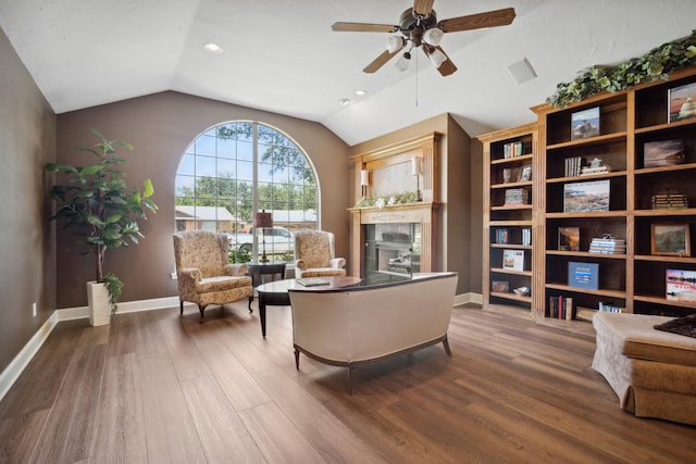 sitting room featuring hardwood / wood-style flooring, ceiling fan, a tiled fireplace, and vaulted ceiling