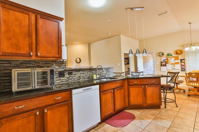 kitchen with sink, tasteful backsplash, dishwasher, pendant lighting, and dark stone counters