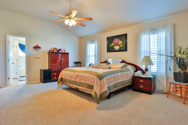 carpeted bedroom with ceiling fan, ensuite bath, vaulted ceiling, and multiple windows