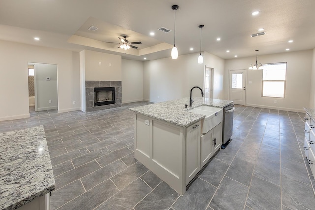 kitchen featuring sink, white cabinetry, hanging light fixtures, a center island with sink, and stainless steel dishwasher