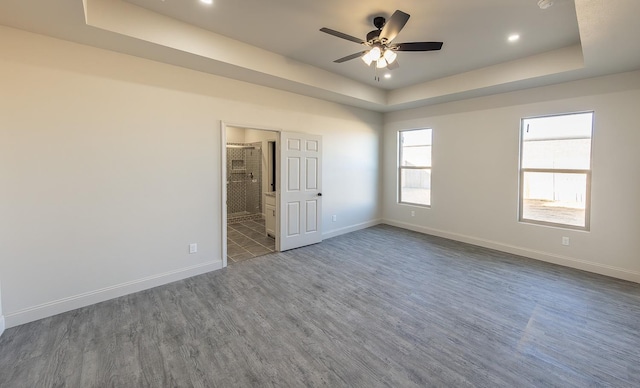 empty room featuring dark hardwood / wood-style flooring, a tray ceiling, and ceiling fan