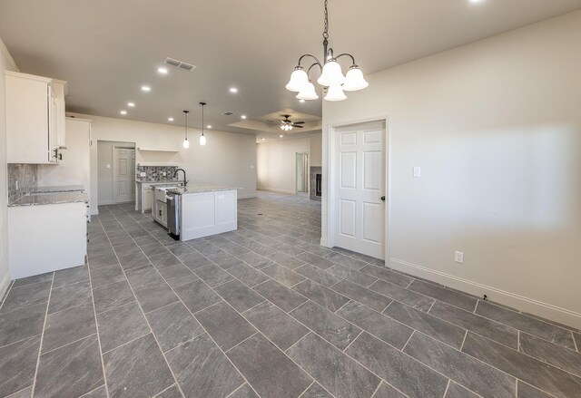 kitchen with ceiling fan with notable chandelier, pendant lighting, white cabinetry, an island with sink, and stainless steel dishwasher