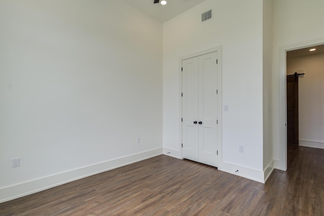 7710 46th St, Lubbock, TX 79407 - unfurnished bedroom featuring dark wood-style flooring, recessed lighting, a barn door, and a closet