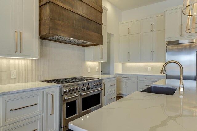 7710 46th St, Lubbock, TX 79407 - kitchen with custom exhaust hood, high end appliances, backsplash, white cabinets, and light stone countertops