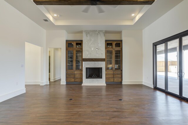 7710 46th St, Lubbock, TX 79407 - unfurnished living room with a tray ceiling, dark wood-type flooring, a ceiling fan, a high end fireplace, and a towering ceiling