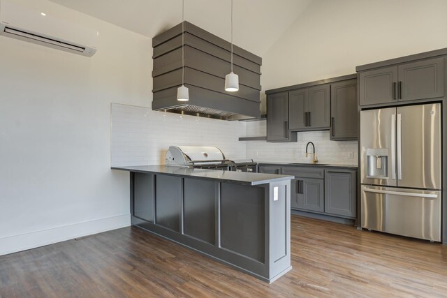 7710 46th St, Lubbock, TX 79407 - kitchen featuring stainless steel fridge with ice dispenser, a wall mounted AC, a peninsula, tasteful backsplash, and wood finished floors