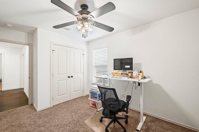 carpeted office with a ceiling fan and baseboards