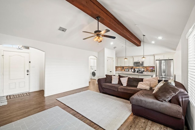 living area with arched walkways, wood finished floors, independent washer and dryer, and ceiling fan
