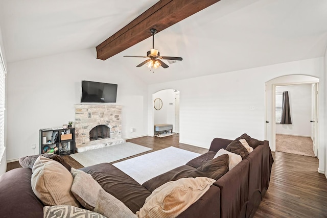living area with arched walkways, dark wood finished floors, a ceiling fan, a fireplace, and baseboards