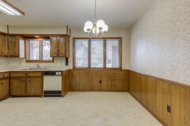 5530 92nd St, Lubbock, TX 79424 - kitchen featuring white dishwasher, brown cabinets, a wainscoted wall, a chandelier, and wallpapered walls