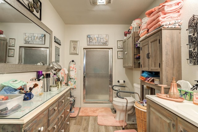 bathroom featuring vanity, a shower with shower door, wood-type flooring, and toilet