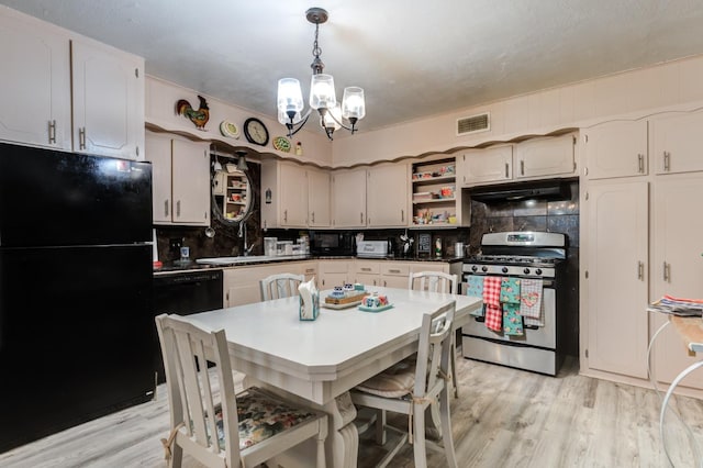 kitchen featuring gas stove, black fridge, decorative light fixtures, light wood-type flooring, and decorative backsplash