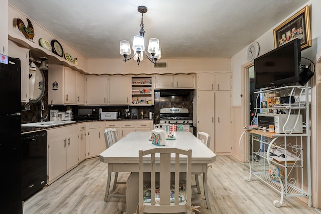 kitchen with pendant lighting, stainless steel gas range, black dishwasher, a notable chandelier, and light hardwood / wood-style floors