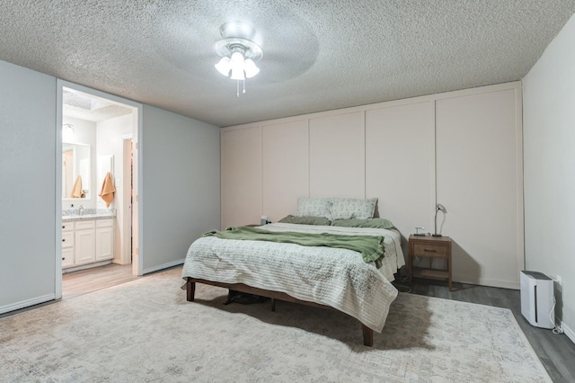 bedroom featuring connected bathroom, sink, a textured ceiling, hardwood / wood-style flooring, and ceiling fan