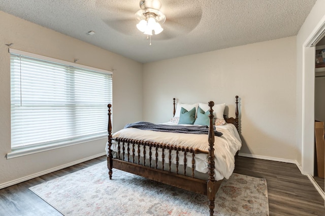 bedroom with ceiling fan, dark wood-type flooring, and a textured ceiling