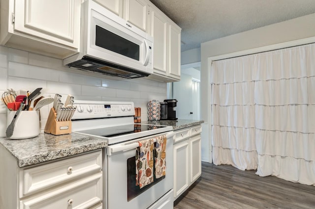 kitchen with white appliances, white cabinetry, dark hardwood / wood-style floors, tasteful backsplash, and light stone countertops