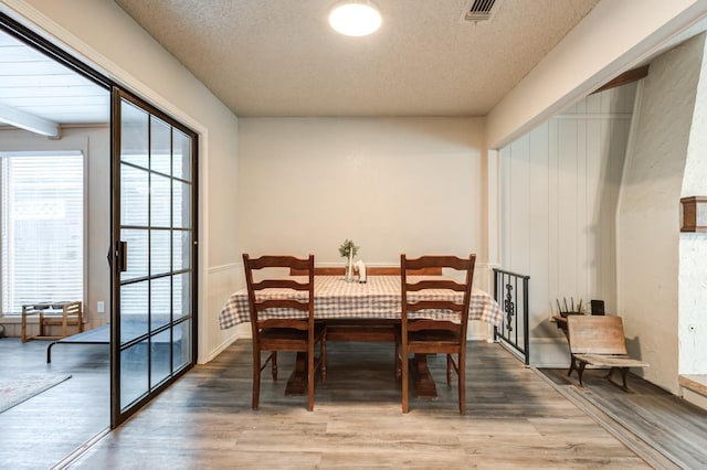 dining space with wood-type flooring and a textured ceiling