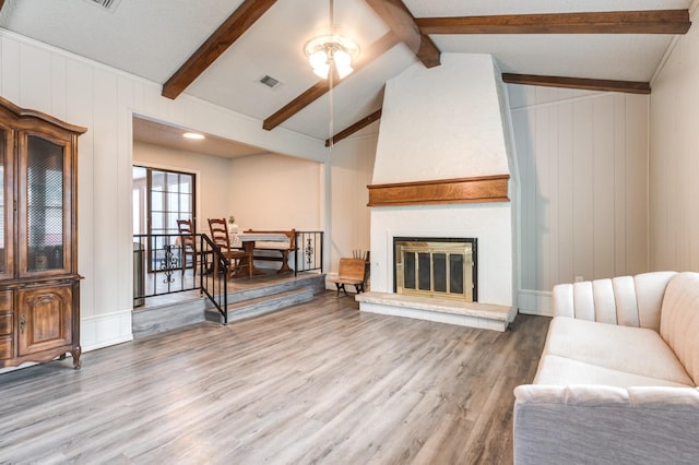 living room with lofted ceiling with beams, a fireplace, and hardwood / wood-style floors