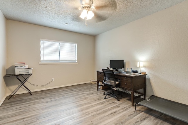 home office with ceiling fan, light hardwood / wood-style floors, and a textured ceiling