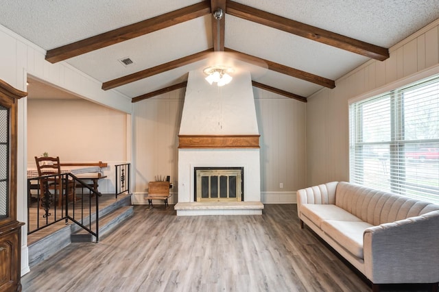 living room with hardwood / wood-style floors, a fireplace, lofted ceiling with beams, and a textured ceiling