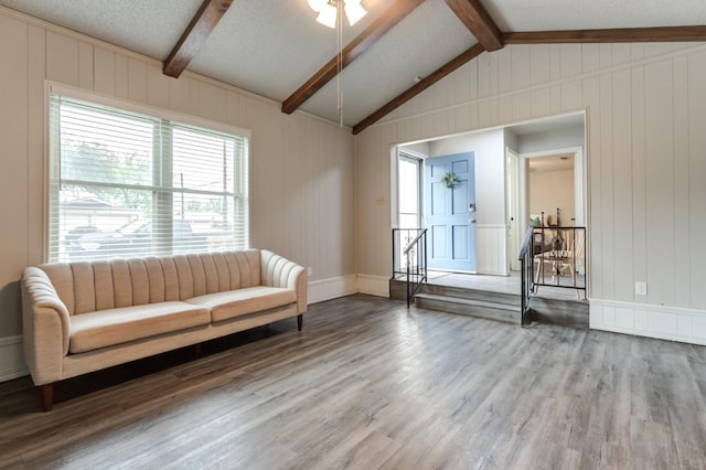 unfurnished room with ceiling fan, wood-type flooring, a textured ceiling, and vaulted ceiling with beams