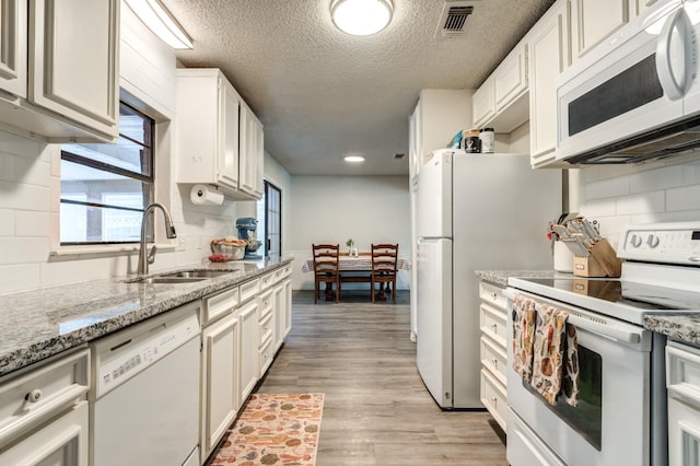 kitchen with white cabinetry, light stone countertops, sink, and white appliances