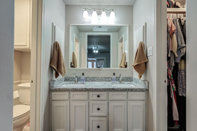 bathroom with vanity, toilet, and a textured ceiling