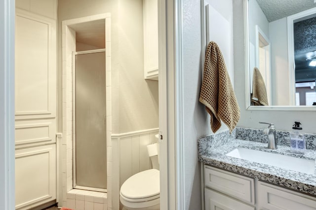 bathroom with vanity, toilet, an enclosed shower, and a textured ceiling