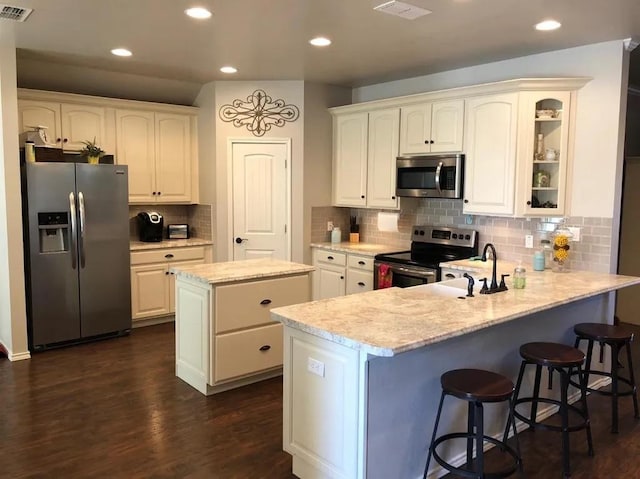 kitchen featuring a kitchen breakfast bar, a center island, kitchen peninsula, stainless steel appliances, and dark wood-type flooring