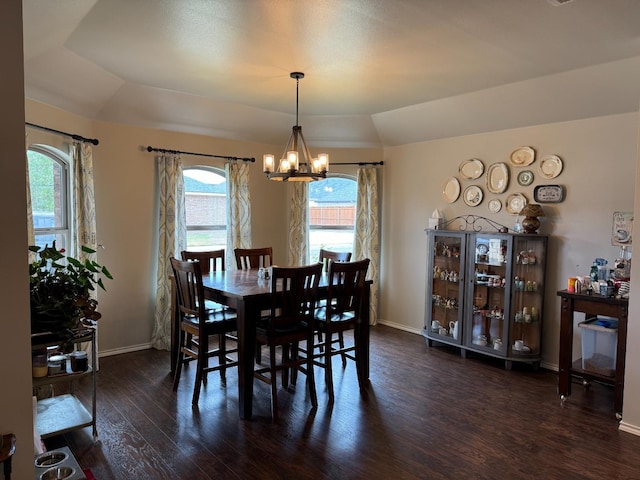 dining room featuring dark wood-type flooring, a tray ceiling, a chandelier, and vaulted ceiling