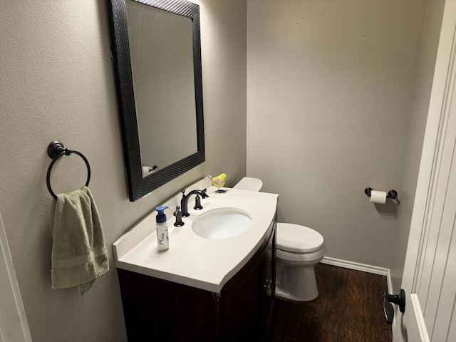 bathroom with hardwood / wood-style flooring, vanity, and toilet