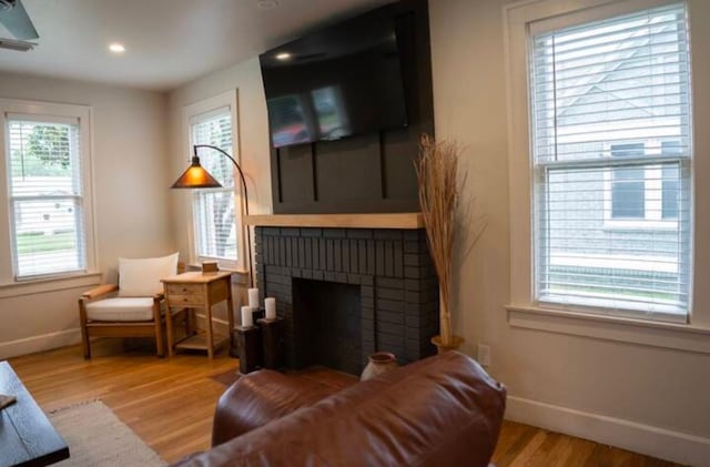 living area with a brick fireplace and light hardwood / wood-style floors