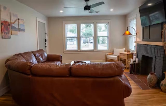 living room with a brick fireplace, hardwood / wood-style flooring, and ceiling fan